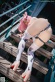 A woman with pink hair is posing on a wooden bench.