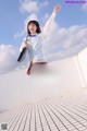A young woman in a school uniform jumping in the air.