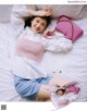 A woman laying on a bed holding a pink purse.