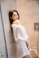 A woman in a white shirt is standing in a shower.