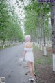 A woman in a white dress walking down a road.