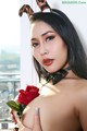 A woman in a devil costume holding a red rose.