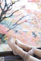 A woman's legs are tied up on a window sill.