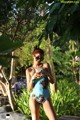 A woman in a blue one piece swimsuit holding a drink.