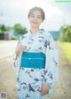 A woman in a blue and white kimono standing on a dirt road.