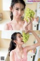 A woman holding a bunch of green grapes in her hand.