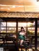 A woman in a green dress is standing in front of a restaurant.