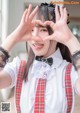 A woman in a school uniform making a heart with her hands.