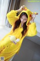 A woman in a yellow pikachu costume is posing for a picture.