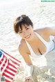 A woman laying on the beach holding an American flag.