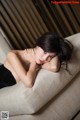 A woman laying on top of a couch with her head resting on her hands.