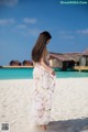 A woman in a white dress standing on a beach.