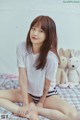 A woman sitting on a bed with a teddy bear.